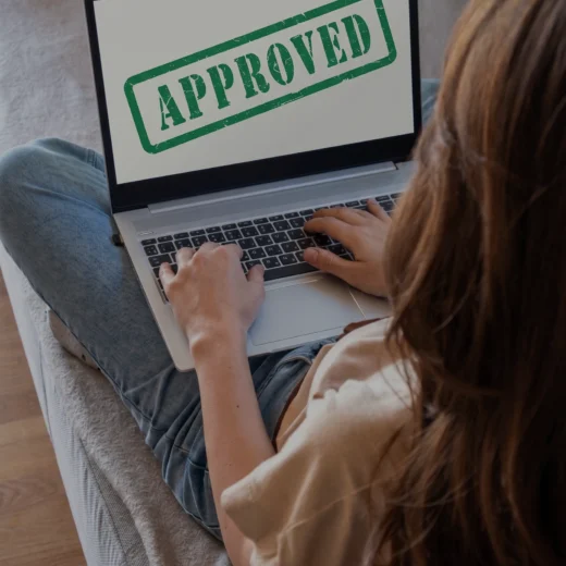 woman looking on laptop screen that has the word approved